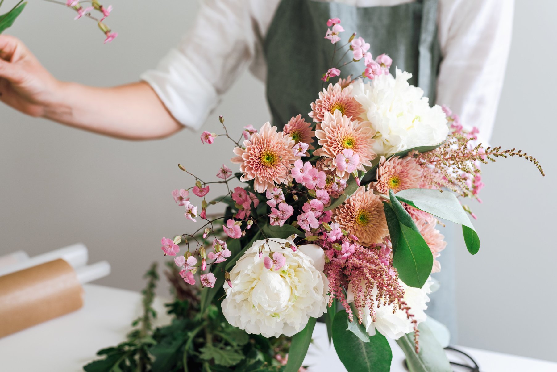 A flower boutique employee creates a flower arrangement.